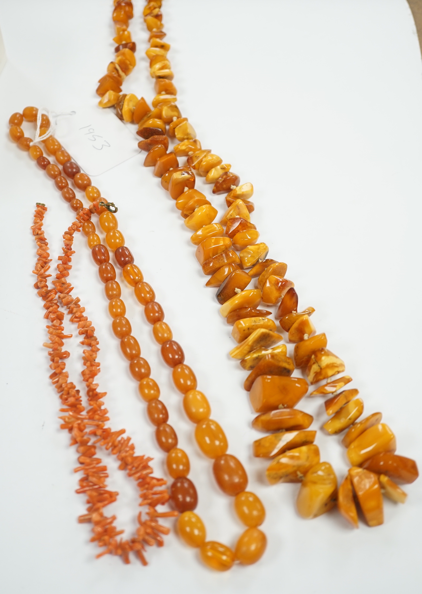 A single strand graduated amber bead necklace, 56cm, gross weight 34 grams, one other amber necklace and a coral necklace.